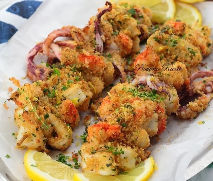 Spiedini di calamari e gamberi gratinati su un piatto