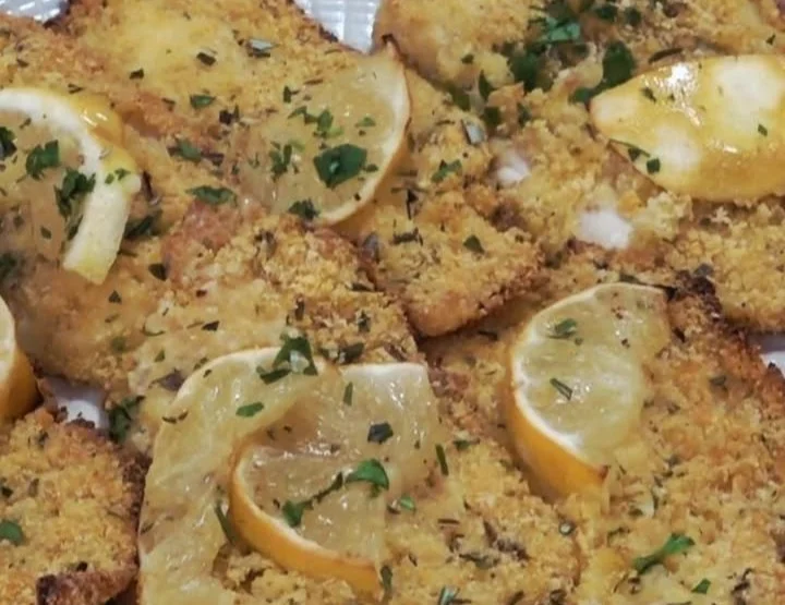 Pollo al limone croccante al forno servito con contorni freschi e limoni