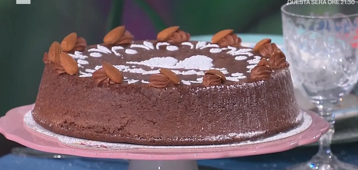 Fetta di Torta Caprese con cioccolato e mandorle su un piatto bianco.