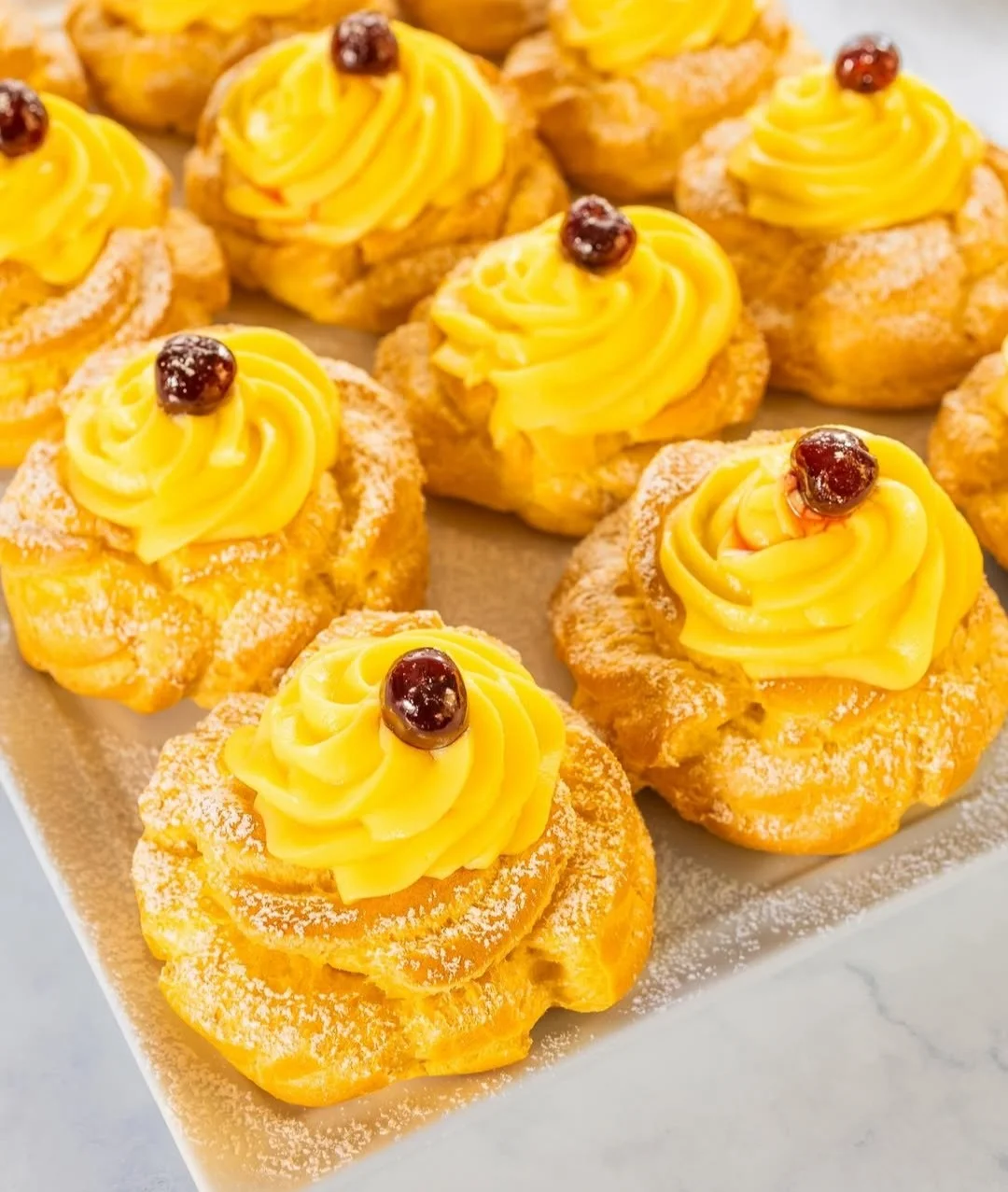 Zeppole di San Giuseppe decorate con crema e ciliegia
