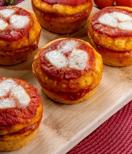 Muffin alla Pizza serviti su un piatto colorato, ricchi di formaggio e pomodoro