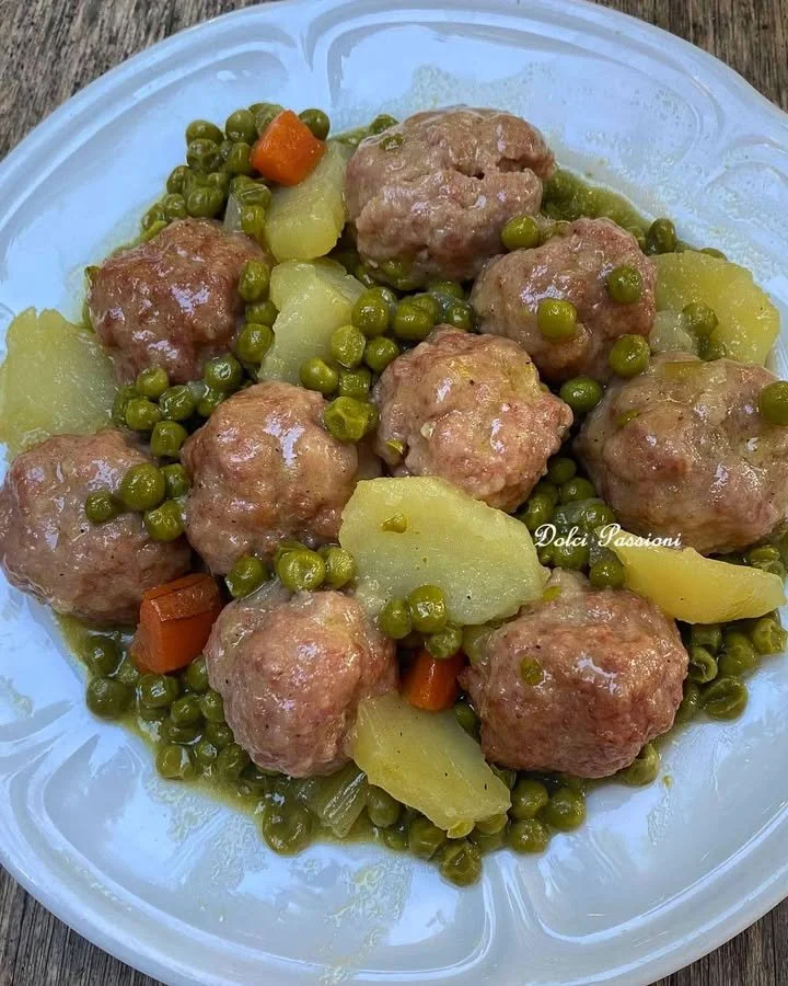 Polpette con piselli, patate e carote servite in un piatto.