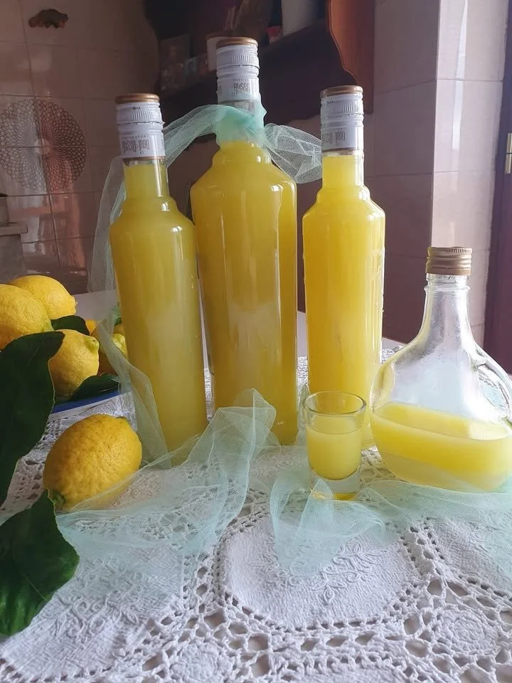 Bottiglia di Limoncello con limoni freschi sullo sfondo.