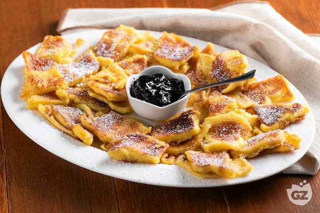 Deliziosa porzione di Kaiserschmarren con zucchero a velo e frutta fresca.