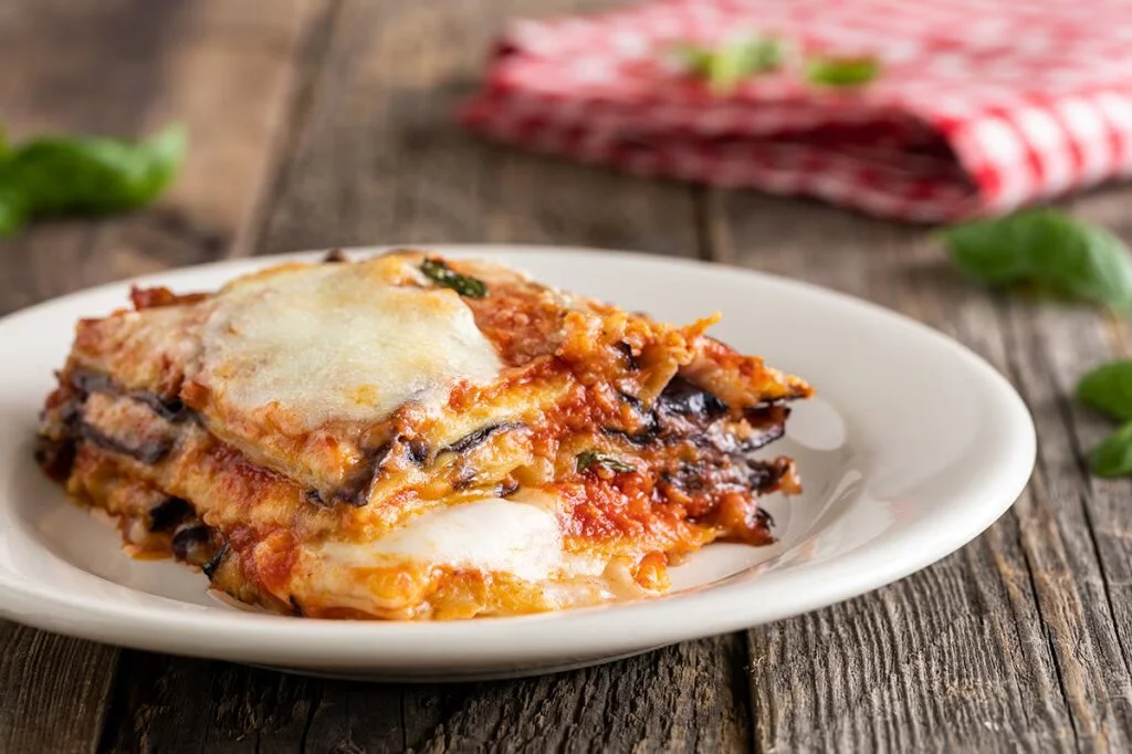 Piatto di parmigiana di melanzane con formaggio fuso e salsa di pomodoro
